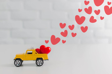 Valentines Day theme,Red hearts in toy yellow truck car carrying to lover.Love delivery concept. - Powered by Adobe