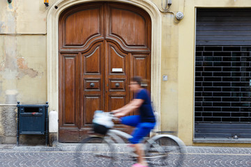 Typical Italian bicycler rides in ancient village in Tuscany, Italy.  Motion blur.