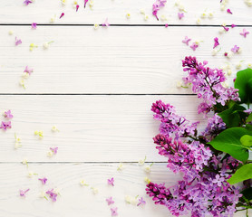 Fototapeta premium Floral pattern of a branch of lilac and other spring flowers on a white wooden background. top view. flat lay. Holiday concept. Copy space