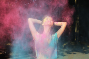 Positive brunette model posing with Holi powder exploding around her