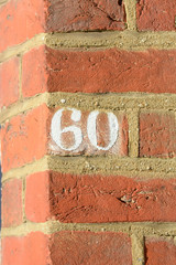 House number 60 sign painted white on wall