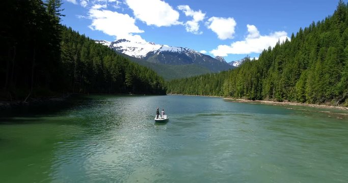 Two men fishing in the river while sailing in the boat on a sunny day  