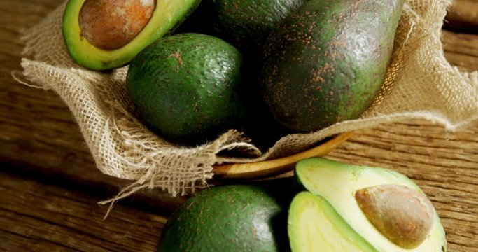 Avocados in jute fabric placed on wooden table  