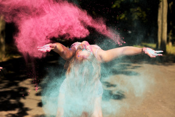 Cool young woman having fun with exploding dry Holi paint