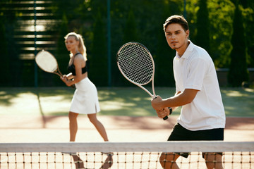 Man And Woman Playing Tennis On Court.