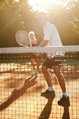 Man And Woman Playing Tennis On Court.