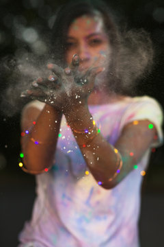 Attractive tanned asian woman having fun with Holi paint posing with garland on her hands