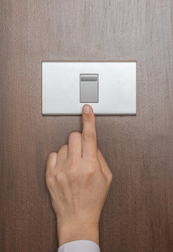 Energy saving concept with business woman's hand turn off switch light button on wood panel