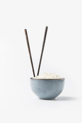 bowl of freshly cooked rice with chopsticks on white surface