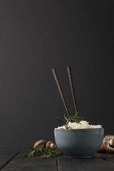 bowl of tasty rice with chopsticks and mushrooms on black tabletop