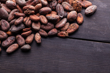 Raw cocoa beans on dark wood