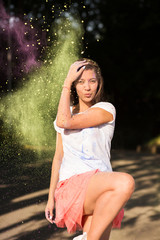 Emotional brunette asian woman playing with dry green paint on Holi colors festival