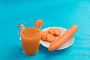 Carrot juice in a glass on a blue background, top view. Concept of a healthy diet, diet.