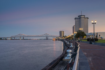 Fototapeta na wymiar View of the Mississippi river from the city of New Orleans riverfront, with the Great New Orleans Bridge on the background in New Orleans, Louisiana, at dusk.
