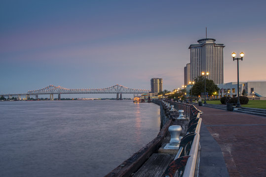 View Of The Mississippi River From The City Of New Orleans Riverfront, With The Great New Orleans Bridge On The Background In New Orleans, Louisiana, At Dusk.