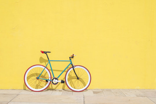 A City bicycle fixed gear on yellow wall