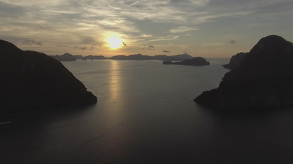 Tropical bay in El Nido sunset. Aerial view: tropical landscape. Sunset sky and mountains rocks of bay. Dreamy sunset among the rocks. Philippines, El Nido. Boats in the sea. Travel concept.