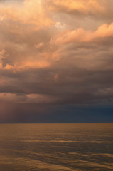 Naklejka na ściany i meble storm clouds on the Azov Sea, illuminated by the setting sun, the sea horizon. vertical composition.