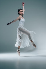 elegant ballerina in white dress dancing in studio