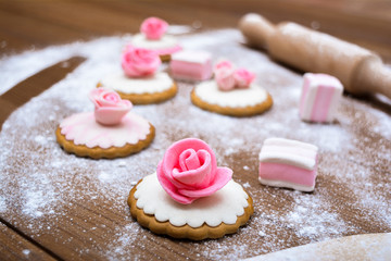 Cakes with mastic, flour, wooden background. Easter cakes.