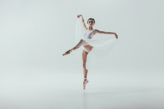 Fototapeta young elegant ballerina dancing in studio, isolated on white