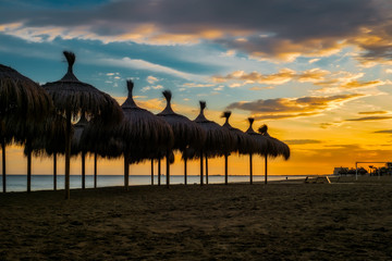 Straw beach umbrellas at sunset