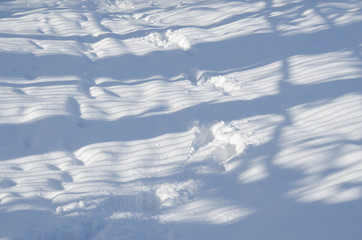 Traces and shadows on the snowdrift. Abstract winter landscape.
