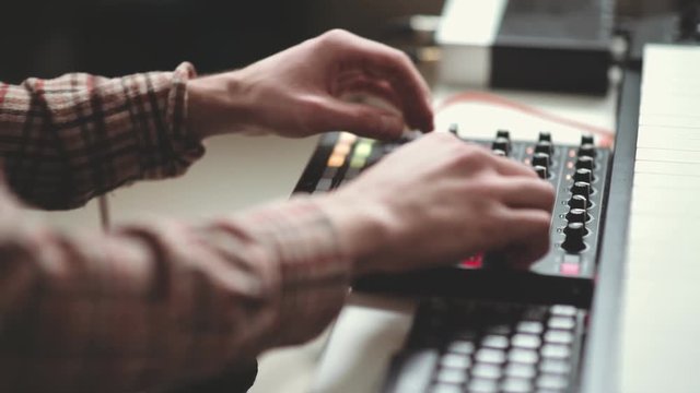 The modern composer writes electronic music, works behind the panel. DJ console: close-up, hands change settings. Creative process of writing music. Music studio.