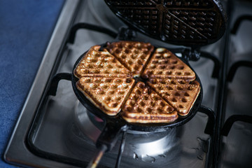 Just cooked, delicious, tasty, hot yogurt pancakes on waffle iron on fire stove in kitchen. Dinner is ready. Sweet golden brown waffles ready to be eaten