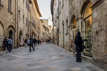 People walking and shopping on the main street of the medieval village, San Gimignano, Siena, Tuscany, Italy