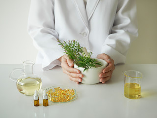 scientist or doctor making herbal medicine with herb leaves , capsule, tablets. hands.