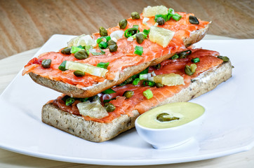 Salmon sandvich on white plate.