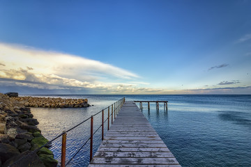 Obraz premium old wooden pier with nobody against a beautiful morning sky.