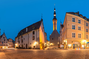Naklejka na ściany i meble Beautiful illuminated street of Medieval Old Town and Town Hall in the morning blue hour, Tallinn, Estonia