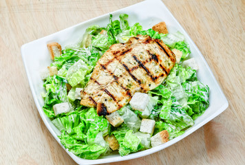 Roasted black pepper lamb steak with salads and fries on a blue round plate. Wooden texture background.