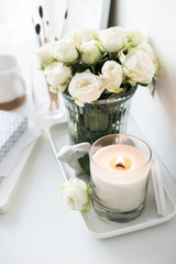 White room interior decor with burning hand-made candle and bouq