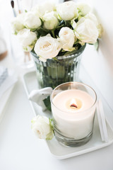 White room interior decor with burning hand-made candle and bouq