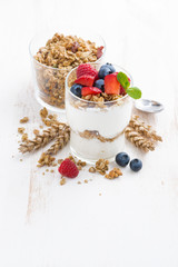 healthy dessert with natural yogurt, muesli and berries on white wooden background, top view