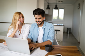 Handsome young man and attractive woman working on laptop