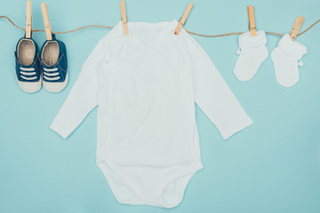 top view of baby clothes drying on rope isolated on blue