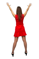 Sexy girl in red dress in stockings and in high heels shoes is standing with rised up hands and is dancing isolated on white background. Back view.