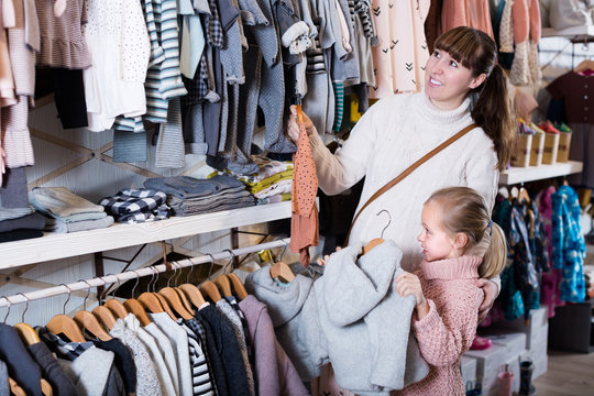 Pregnant mother and daughter choosing clothes for baby