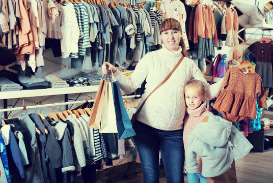 Mother and girl boasting purchases in cloths shop