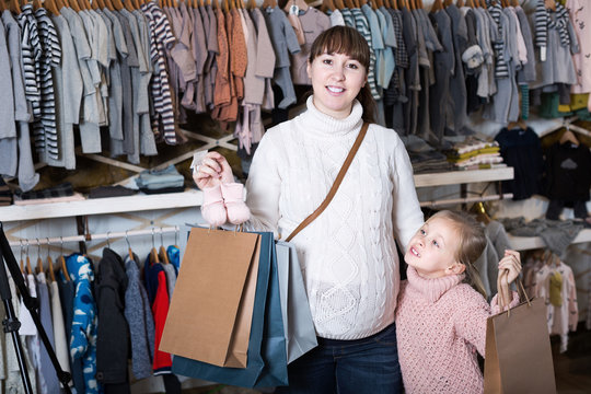 Smiling pregnant woman and girl boasting purchases