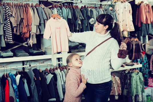 Pregnant mother and daughter purchasing clothes