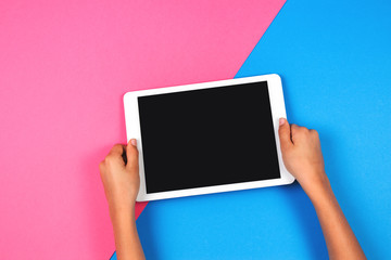 Kid hands with tablet computer on pink background.