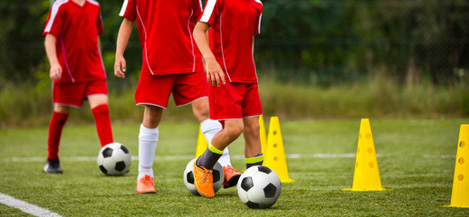 Soccer camp for kids. Children training soccer skills with balls and cones. Soccer slalom drills to...
