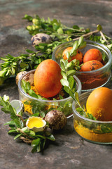 Easter greeting card with colored yellow orange eggs in spices with quail eggs, yolk and green branches over old metal background. Top view, space