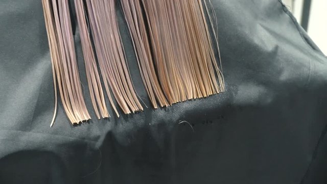 male hairdresser hold in hand between fingers lock of hair, comb and scissors closeup. Trim the tips of the hair by scissors. stages of hair salon haircuts. wash hair before the haircut.