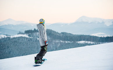 Female snowboarder enjoying skiing in mountains in the evening on the slope at winter ski resort in the mountains copyspace stunning view scenery landscape recreation concept